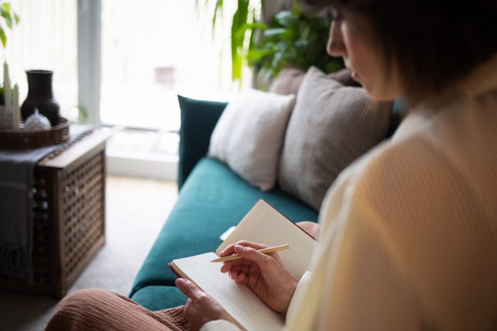 Woman journaling on a sofa at home