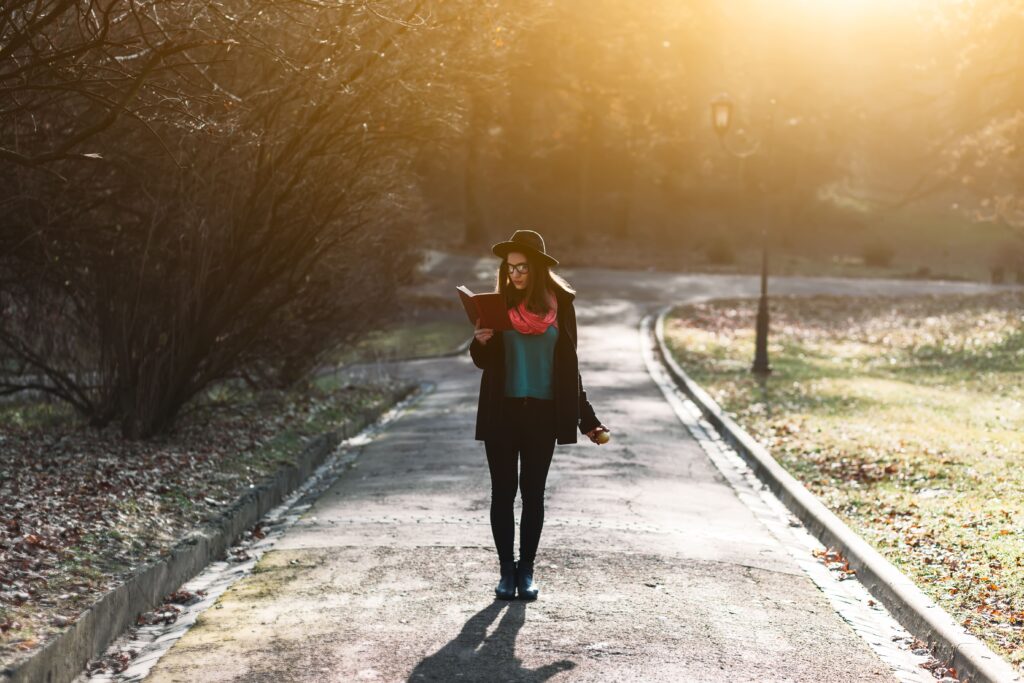 Woman reading on a pathway in golden evening light